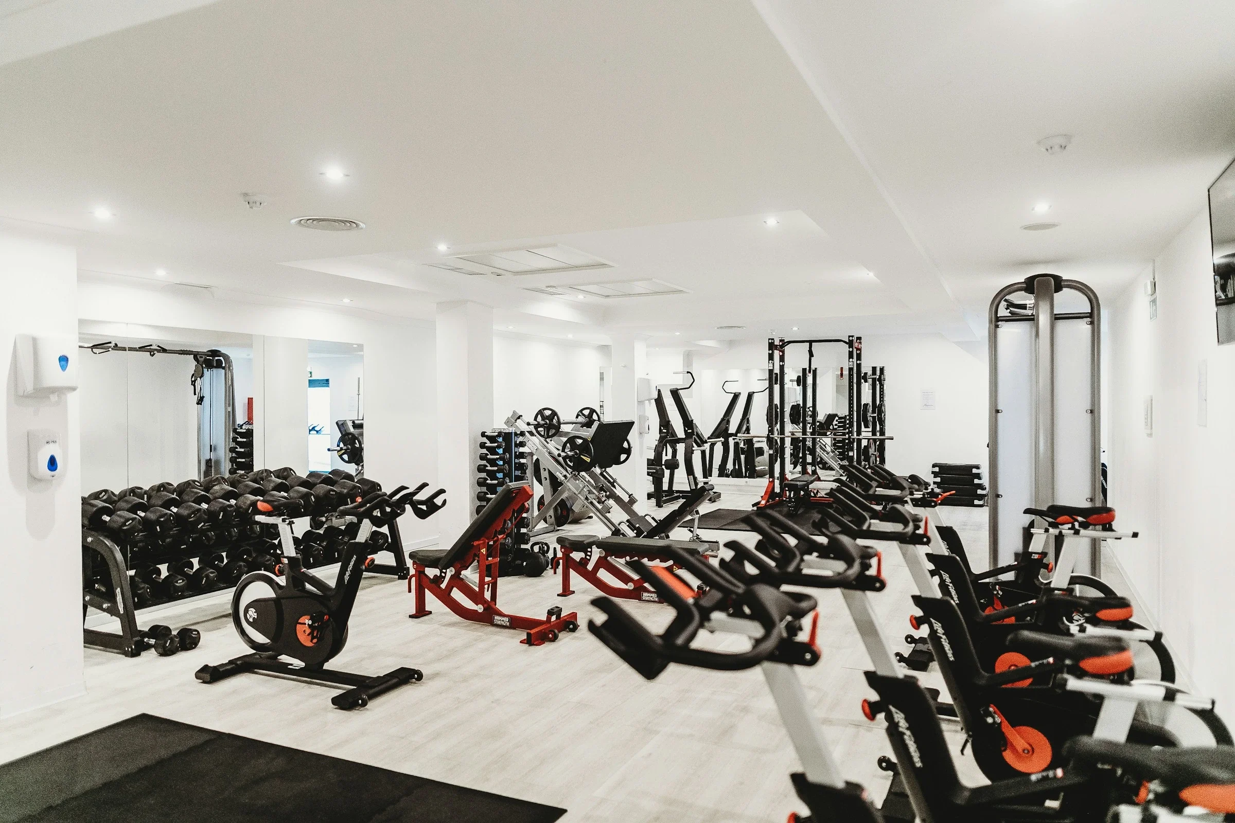 Gimnasio vacío con bicicletas estáticas, bancos y máquinas de musculación