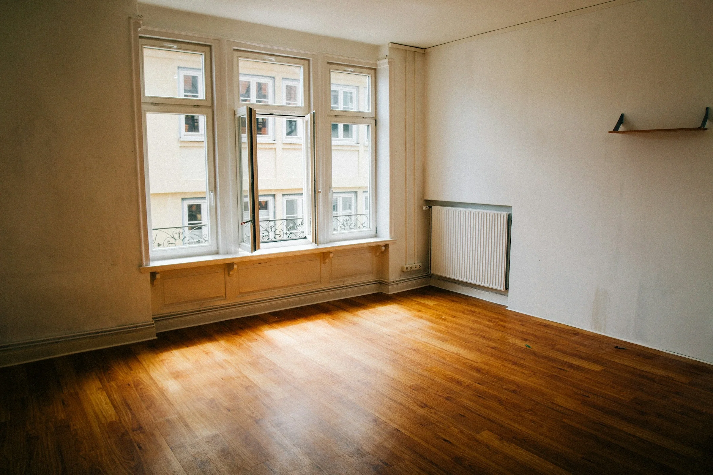 Habitación vacía con suelo de madera y un gran ventanal