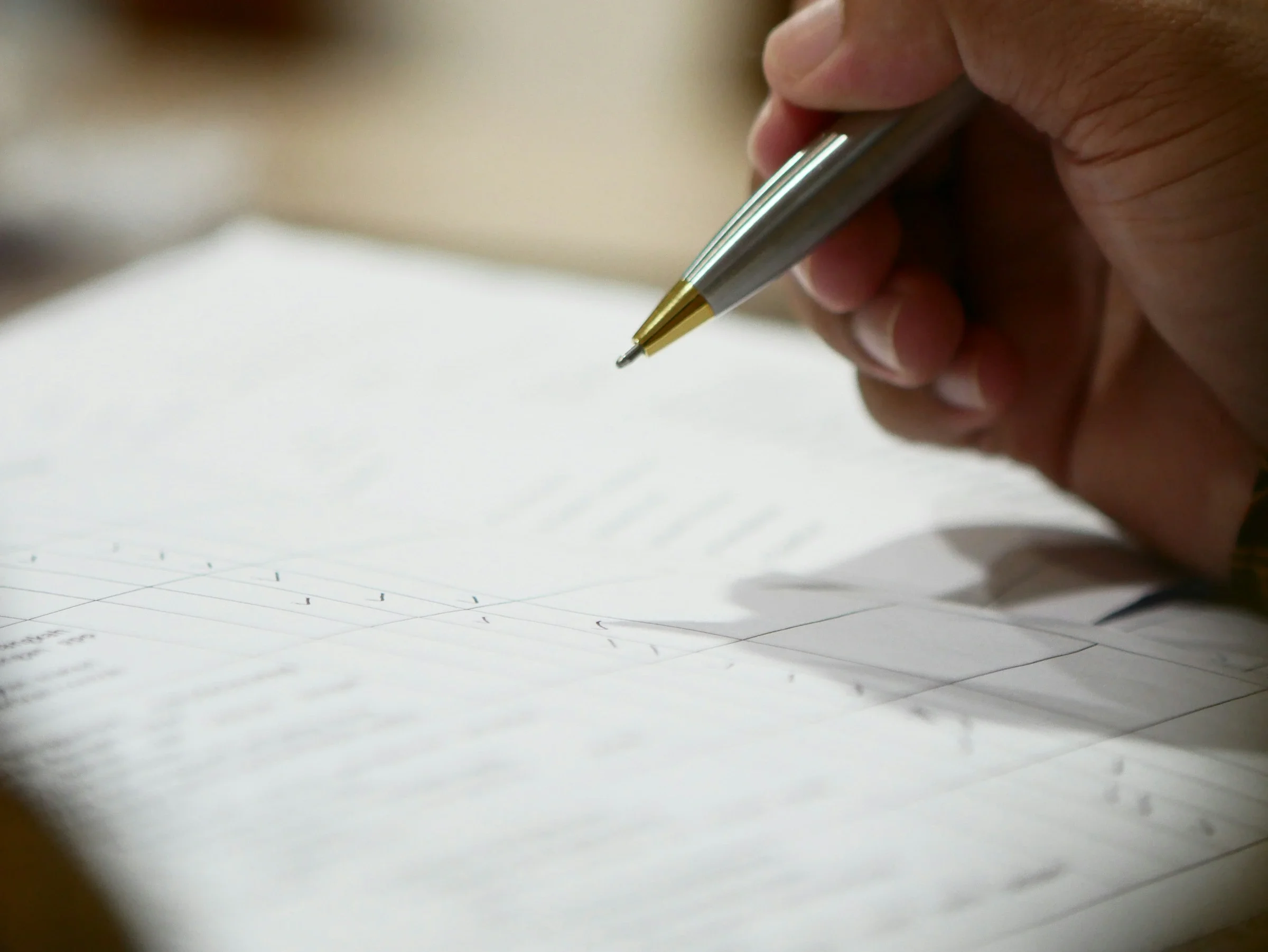 Mano con un bolígrafo plateado a punto de firmar un formulario